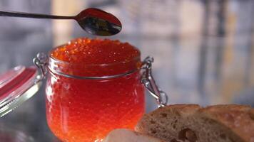 Man's hands takes a spoonful of red caviar and puts it on a piece of bread. Editing two frames. Close-up. video