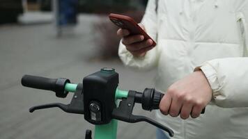 Handsome man using smartphone app. Guy approaches an electric scooter and using mobile phone app NFC contactless locker on bike bicycle in sharing parking lot. video