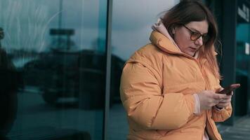 Digital AI chatbot, Happy Caucasian woman in yellow jacket and sunglasses using mobile smartphone with AI chatbot for online information in city town, conversation assistant. video