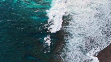 Crashing waves in sea, top down view. Ocean waves above drone view video
