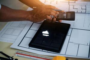 A person is using a calculator and a tablet on a table photo