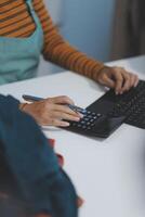 A person typing on a keyboard and holding a pen photo
