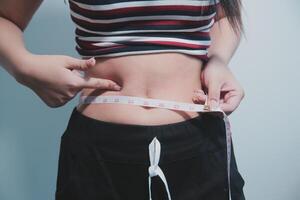 A woman measuring her waist with a tape measure photo