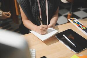 A person is writing on a notebook while sitting at a desk photo