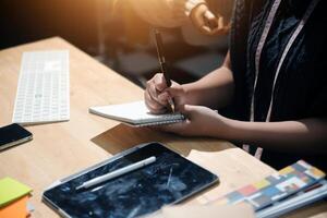 A person is writing on a notebook while sitting at a desk photo