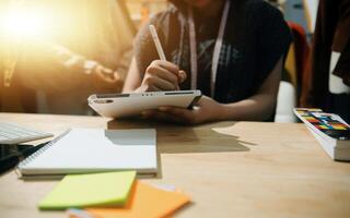 A woman is writing on a notepad while sitting at a desk photo