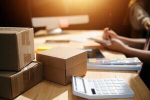 A woman is working on a computer with a calculator and boxes photo