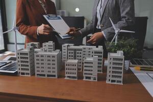 Two people standing near a table with model buildings photo