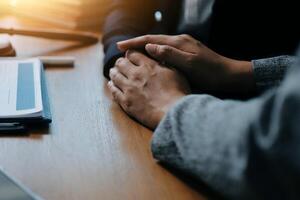 Two people holding hands at a desk with a laptop photo