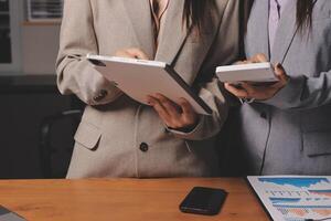 Two business women standing in front of a desk photo