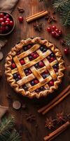 Delicious homemade berry pie with a golden lattice crust, surrounded by fresh cranberries, cinnamon sticks, and star anise on a rustic wooden table. photo