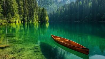 A serene scene of a wooden canoe on a clear lake, enveloped by dense forest and towering mountains under a bright sky. photo