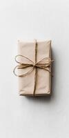 Brown box with a white ribbon tied around it. The box is sitting on a white surface photo