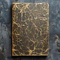 Luxurious notebook with a gold marble pattern on a dark wooden surface, ideal for creative projects and sophisticated stationery themes. photo