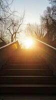 A serene sunrise scene with sunlight streaming over an urban staircase, silhouetting bare trees against a golden sky. photo