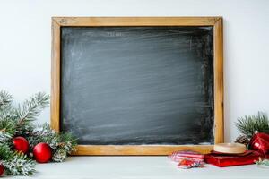 Empty chalkboard surrounded by Christmas ornaments and pine branches, perfect for holiday-themed designs and messages. photo
