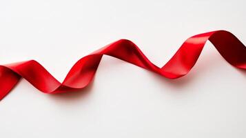 Red ribbon is curled up on a white background. The ribbon is long and has a wavy appearance photo