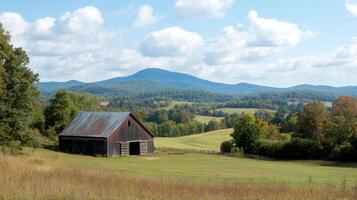 A rustic barn sits in a field with a mountain in the background photo