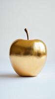 A shiny golden apple on a white background, representing luxury, wealth, and elegance in a minimalist style. photo