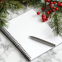 Open notebook with pen on marble, framed by pine branches and red berries, perfect for holiday writing or planning. photo
