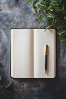 Open blank notebook with pen on a rustic table, surrounded by green leaves, perfect for writing or journaling inspiration. photo