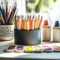 A vibrant collection of colored pencils and paints on a sunlit desk, perfect for art and creativity enthusiasts. photo
