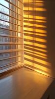 Sunlight filters through window blinds, creating warm shadows on a wall, evoking a cozy and serene atmosphere. photo