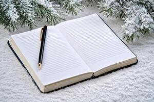 Open notebook with a pen on snow, framed by frosted pine branches, capturing a serene winter scene. photo