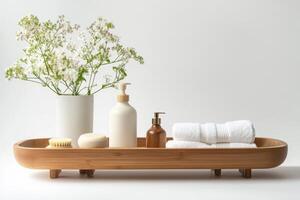 A wooden tray with a vase of flowers and a bottle of lotion on it. The tray is placed on a white surface photo