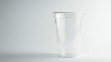 A clear plastic cup is sitting on a white background. The cup is empty. There is no liquid in the cup photo