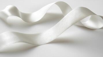 A white ribbon is curled up on a white background. The ribbon is long and thin. It is not a real ribbon, but a digital image photo