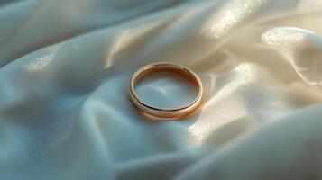 A gold ring is on a white cloth. The cloth is on a table photo
