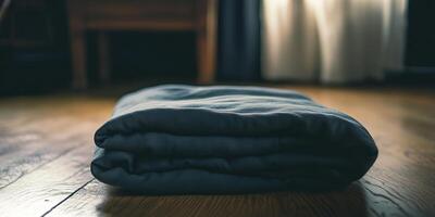A neatly folded blanket on a wooden floor, illuminated by natural sunlight streaming through soft curtains. photo