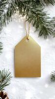 Gold tag with a white background and a pine tree in the background. The tag is hanging from a tree branch photo