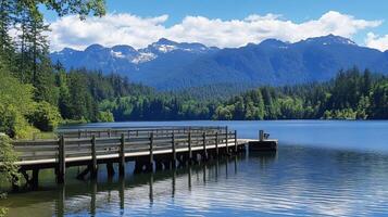Tranquil scene of a wooden dock extending into a calm mountain lake, surrounded by lush forests and majestic mountains. photo