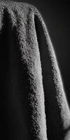 A detailed close-up of a textured fabric, showcasing intricate patterns and dramatic lighting in monochrome. photo