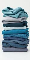 A neatly stacked pile of blue and gray clothing showcasing different textures and fabrics against a light background. photo