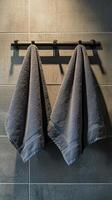 Elegant gray towels on a sleek black rack, enhancing a modern bathroom with dark tile design. photo