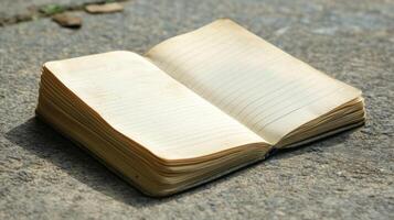 An open vintage notebook with lined pages on a rustic stone surface, ideal for writing or sketching in an outdoor setting. photo
