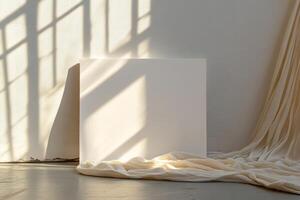 A blank canvas illuminated by sunlight, surrounded by soft draped fabric, creating a serene and minimalist interior scene. photo