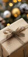 Gold and silver wrapped gift box with a bow on top. The box is sitting on a tree branch photo