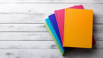 A stack of books with the top one being yellow. The books are arranged in a rainbow order photo