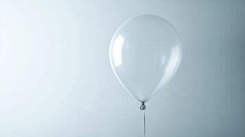 A single white balloon floats against a soft blue background, creating a minimalist and serene scene. photo