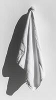 Minimalist White Towel Hanging on Wall with Dramatic Shadows in Bright Sunlight photo