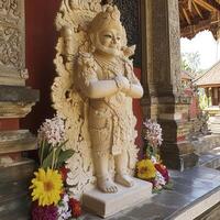 Beige Stone Statue in Balinese Temple with Floral Offerings photo