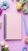 Elevate Your Creative Space A Stunning Flat Lay of a Blank Pink Notebook Surrounded by Vibrant Spring Flowers and a Matching Blue Pen, Perfect for Capturing Your Thoughts, Ideas, and Inspirations photo