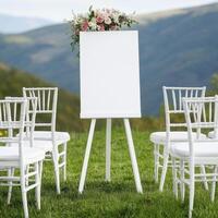 Outdoor Wedding Ceremony with Blank Canvas on Easel A picturesque scene of a wedding set against a stunning mountain backdrop, featuring a blank canvas on a white easel adorned with delicate pink and photo