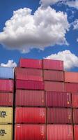Stacked Shipping Containers A Colorful Display of Global Trade and Logistics, showcasing red, pink, blue, and yellow containers against a vibrant blue sky dotted with fluffy white clouds photo