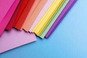 Vibrant Colored Paper Stacks on Light Blue Surface An Abstract Display of Artistic Craft Materials and Supplies Explore a spectrum of colorful texture overlays and backgrounds Discover captivating photo