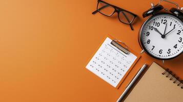 Orange Background Flatlay of Office Supplies and Clock photo